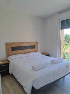 een slaapkamer met een groot wit bed met 2 kussens bij Casa en Tarela, Porto do Son in Porto do Son