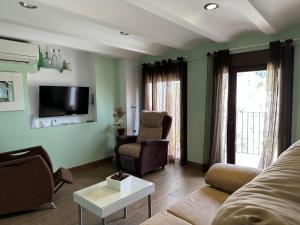 a living room with a couch and a chair and a tv at Alojamientos Peña del Rey in Cazorla