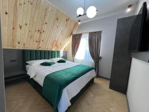 a bedroom with a bed with green sheets and a television at CABANA 7 CRESTE in Borşa