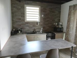 a kitchen with a table and a sink and a stove at aux 4 saisons maison l'opaline in Le Tampon