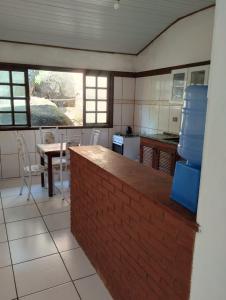 uma cozinha com um balcão de tijolos e uma mesa e cadeiras em Refugio Das Pedras em Paraty