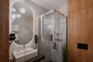 a bathroom with a sink and a shower with a mirror at APARTHOTEL KLEOSIN in Kleosin