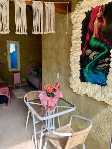una stanza con un tavolo e un dipinto di una sirena di Gruta da Sereia Suítes Ubatuba a Ubatuba