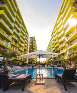 una piscina con sillas y una sombrilla junto a algunos edificios en Studio Alezzi Beach Resort Ely en Năvodari