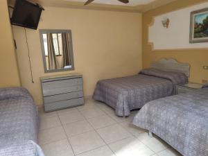 a hotel room with two beds and a television at Hotel Posada California in Aguascalientes