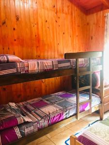 two bunk beds in a room with wooden walls at Cabañas El Portal in Jardín América
