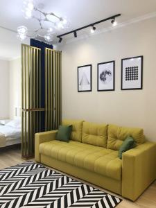 sala de estar con sofá amarillo en una habitación en Стильная квартира в ЖК бизнес класса AVENUE 5 en Astaná