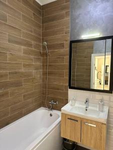 een badkamer met een wastafel, een bad en een spiegel bij Стильная квартира в ЖК бизнес класса AVENUE 5 in Astana