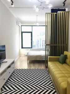 un soggiorno con divano giallo e TV di Стильная квартира в ЖК бизнес класса AVENUE 5 a Astana