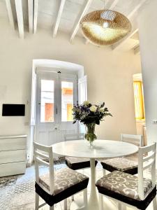 einen weißen Tisch mit Stühlen und eine Vase aus Blumen in der Unterkunft Tuna House in Carloforte