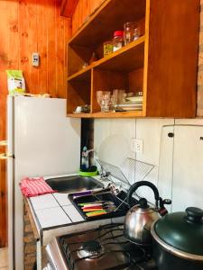 a kitchen with a stove and a sink and a refrigerator at Cabañas El Portal in Jardín América