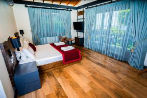 a bedroom with a bed with blue curtains and a wooden floor at Club Porto Amore Hotel Adults Only in Alanya