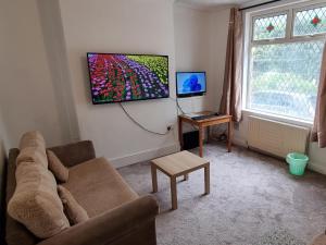 a living room with a couch and a flat screen tv at 4 Bedroom House in Central Rochdale cul-de-sac Free Parking & Fast Wi-Fi in Rochdale