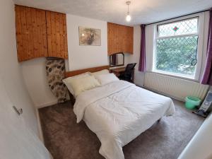 una camera con un letto bianco e una finestra di 4 Bedroom House in Central Rochdale cul-de-sac Free Parking & Fast Wi-Fi a Rochdale