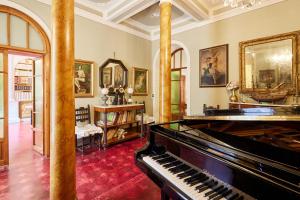 a living room with a piano and paintings on the walls at Villa Augusto in Cortona