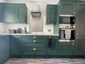 a green kitchen with green cabinets and a microwave at The Secret Nook in Maryport
