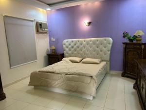 ein Schlafzimmer mit einem Bett und einer lila Wand in der Unterkunft ليلتنا in Ha'il