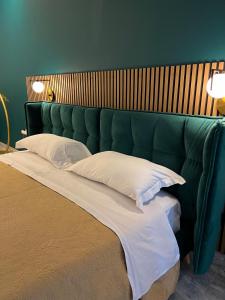 a bed with a green headboard and white pillows at Loft Sirmione in Sirmione