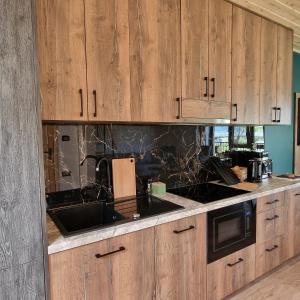 a kitchen with wooden cabinets and a black counter top at Przystań nad Sanem in Tyrawa Solna