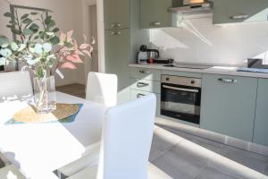 a white kitchen with a table and white chairs at Roma Aurelio appartamento con piscina in Rome