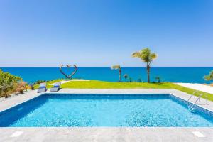 una piscina con el océano en el fondo en Villa Beach Heaven, en Pomos