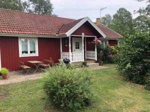 une maison rouge avec une véranda et une table dans l'établissement Röda stugan, à Köpingsvik