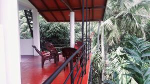 a porch of a house with chairs and palm trees at Rawana Mountain View in Ella