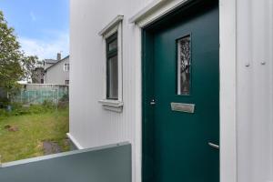 uma porta verde numa casa branca com uma janela em Bright and elegant apartment em Reykjavík
