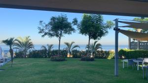 uma vista para um relvado com palmeiras e para o oceano em L'Hotel De Mon Pere em Jbeil