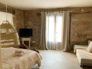 1 dormitorio con 1 cama, TV y ventana en El Reposo de la Grulla, en Perales del Puerto