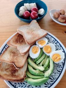 a plate with eggs and toast and a bowl of fruit at Hostal CasAlé Usaquén in Bogotá