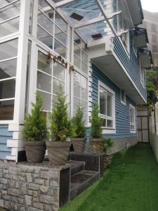 a house with potted trees on the front porch at Pinnacle Vesta Botique Stay in Mussoorie