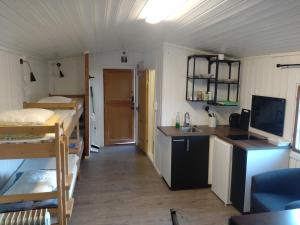 a small room with a bed and a kitchen with a sink at Rondane Friluftssenter Rondetunet in Brenn