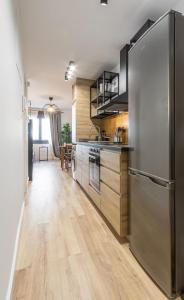 a kitchen with a stainless steel refrigerator and wooden floors at Maior 5 Apartamentos in Verín