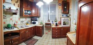 una cocina con armarios de madera y electrodomésticos blancos en Punta Family House, en San Giovanni la Punta