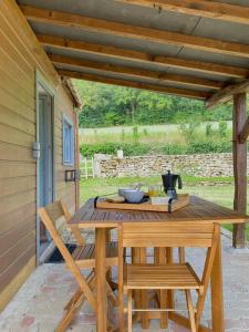 een houten tafel en 2 stoelen op een patio bij Petite maison dans la prairie in Marmeaux
