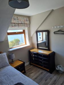 een slaapkamer met een bed, een dressoir en een spiegel bij sea view apartment in Letterkenny