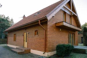 a wooden house with a balcony on the side of it at BASH Village House in Ventspils