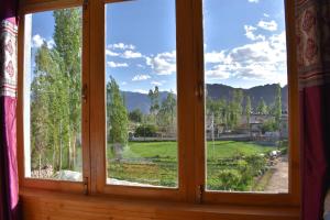a window with a view of a field and mountains at Kushu Guest House in Leh