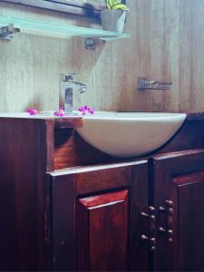 un baño con un lavabo blanco con flores rosas. en AMOUR AT TURTLE BEACH en Tangalle