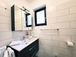 ein weißes Badezimmer mit einem Waschbecken und einem Spiegel in der Unterkunft Friesenhain Ferienwohnungen in Tating