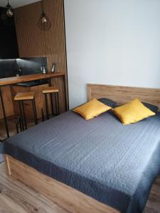 特切夫的住宿－Apartament Kozigród，一间卧室配有一张带两个黄色枕头的床
