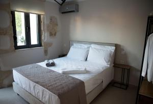 a bedroom with a bed with white sheets and a window at Myra city House in Chania Town