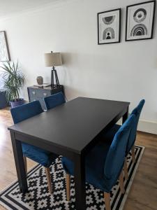 una mesa negra con sillas azules en la sala de estar. en 2 bed flat, Bounds Green, Piccadilly line, London N11 en Londres