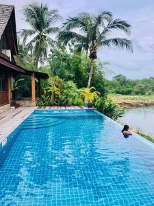 a person in a swimming pool next to a house at Nanai Resort Salakphet in Ko Chang