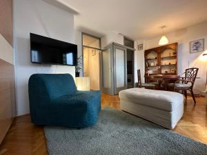 ein Wohnzimmer mit einem blauen Stuhl und einem TV in der Unterkunft Lanište - Prelijep stan, balkon, wifi + besplatan parking in Zagreb