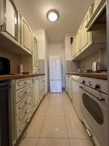 eine Küche mit einem weißen Kühlschrank und Fliesenboden in der Unterkunft Lanište - Prelijep stan, balkon, wifi + besplatan parking in Zagreb