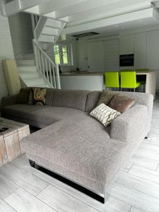 un gran sofá en una sala de estar con una escalera en De Zwarte Els, en Hulshout