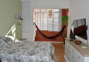 1 dormitorio con 1 cama y TV en Studio Miguel Lemos, en Río de Janeiro