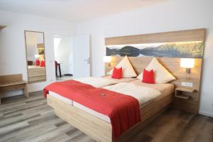 a bedroom with a large bed with red pillows at Hotel Stremme in Gummersbach
